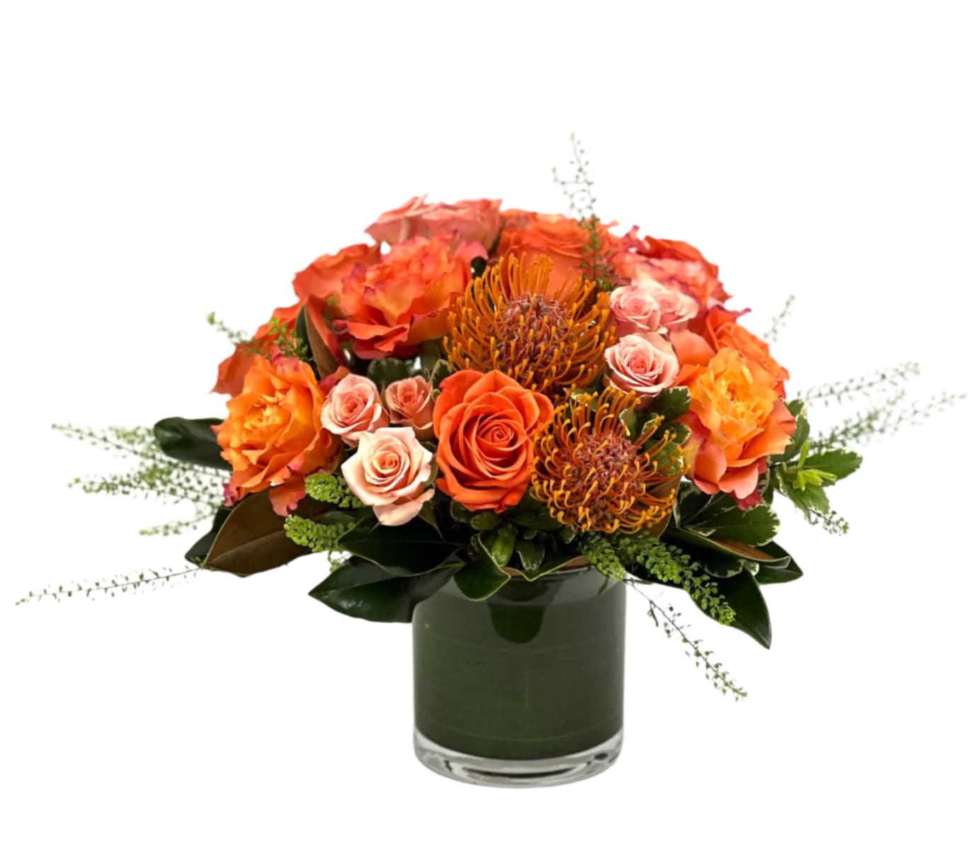 Vibrant floral arrangement featuring orange roses, protea, and lush greenery in a chic glass vase.
