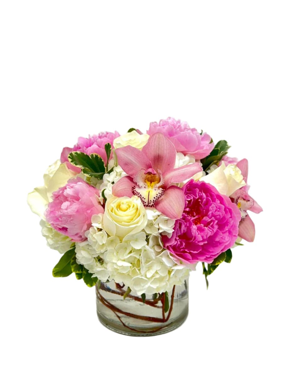 Beautiful mixed flower bouquet featuring pink orchids, peonies, and white roses in a glass vase.