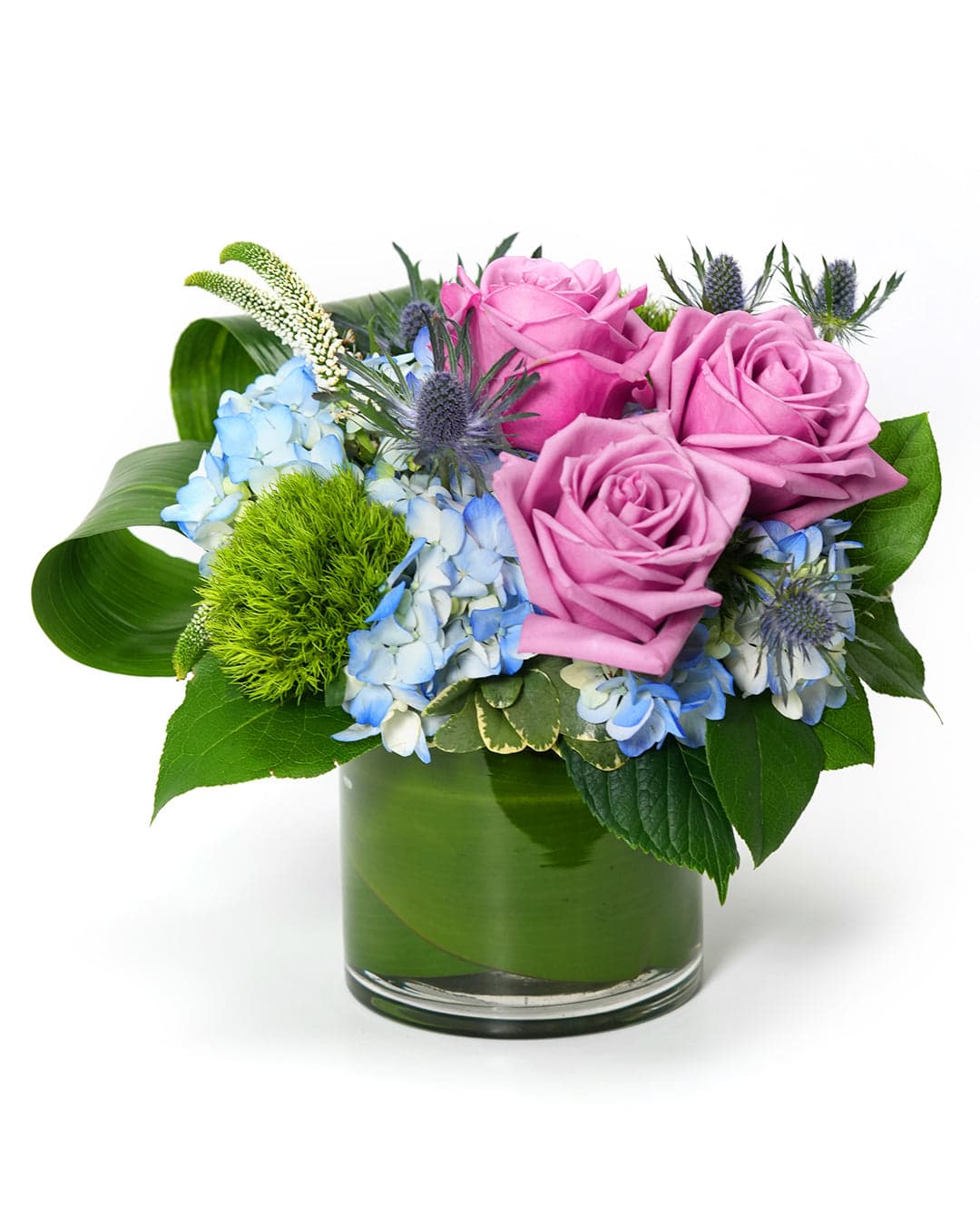 Beautiful bouquet featuring pink roses, blue hydrangeas, and green accents in a stylish glass vase.