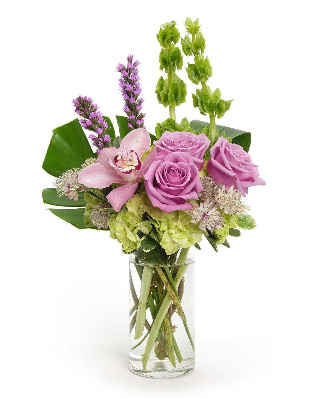 Beautiful arrangement of lavender roses, orchids, and green accents in a clear glass vase. Perfect for any occasion.