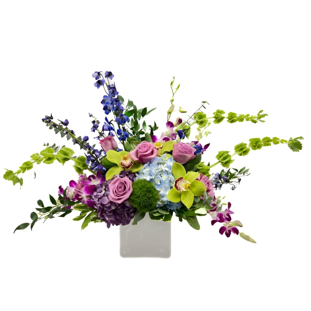 Elegant floral arrangement featuring pink roses, vibrant orchids, and lush greenery in a modern white vase.