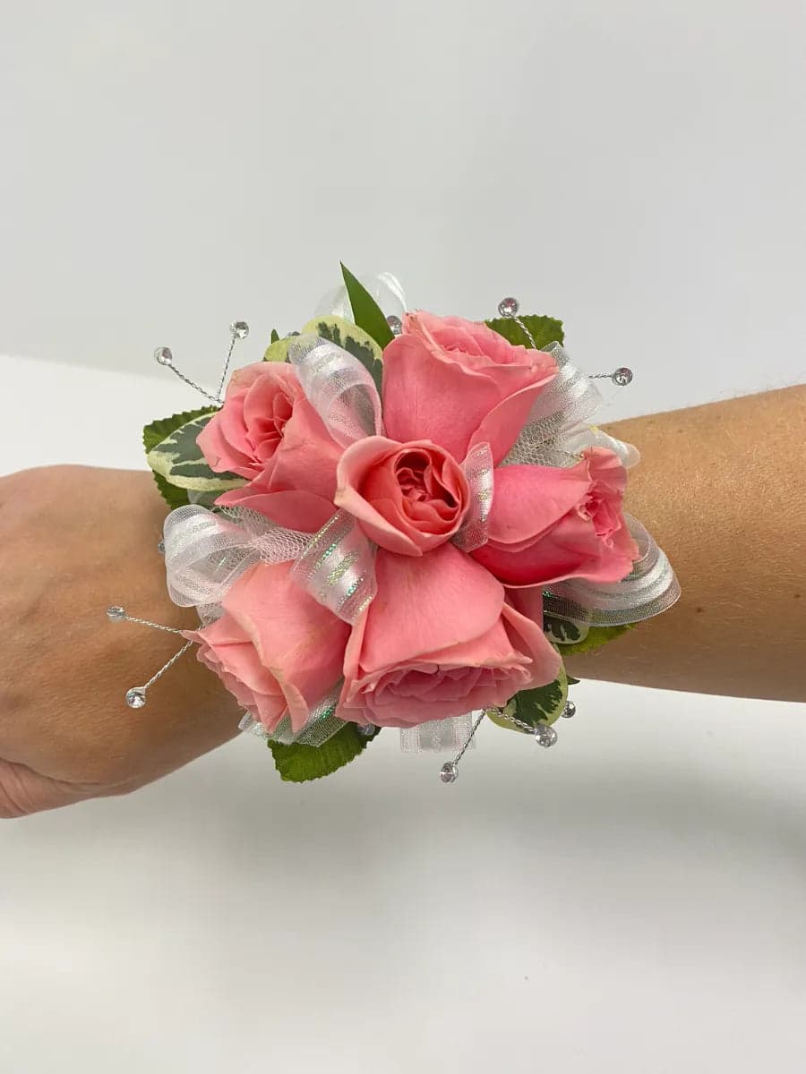 Beautiful pink rose wrist corsage with delicate ribbons and accents, perfect for any special occasion.