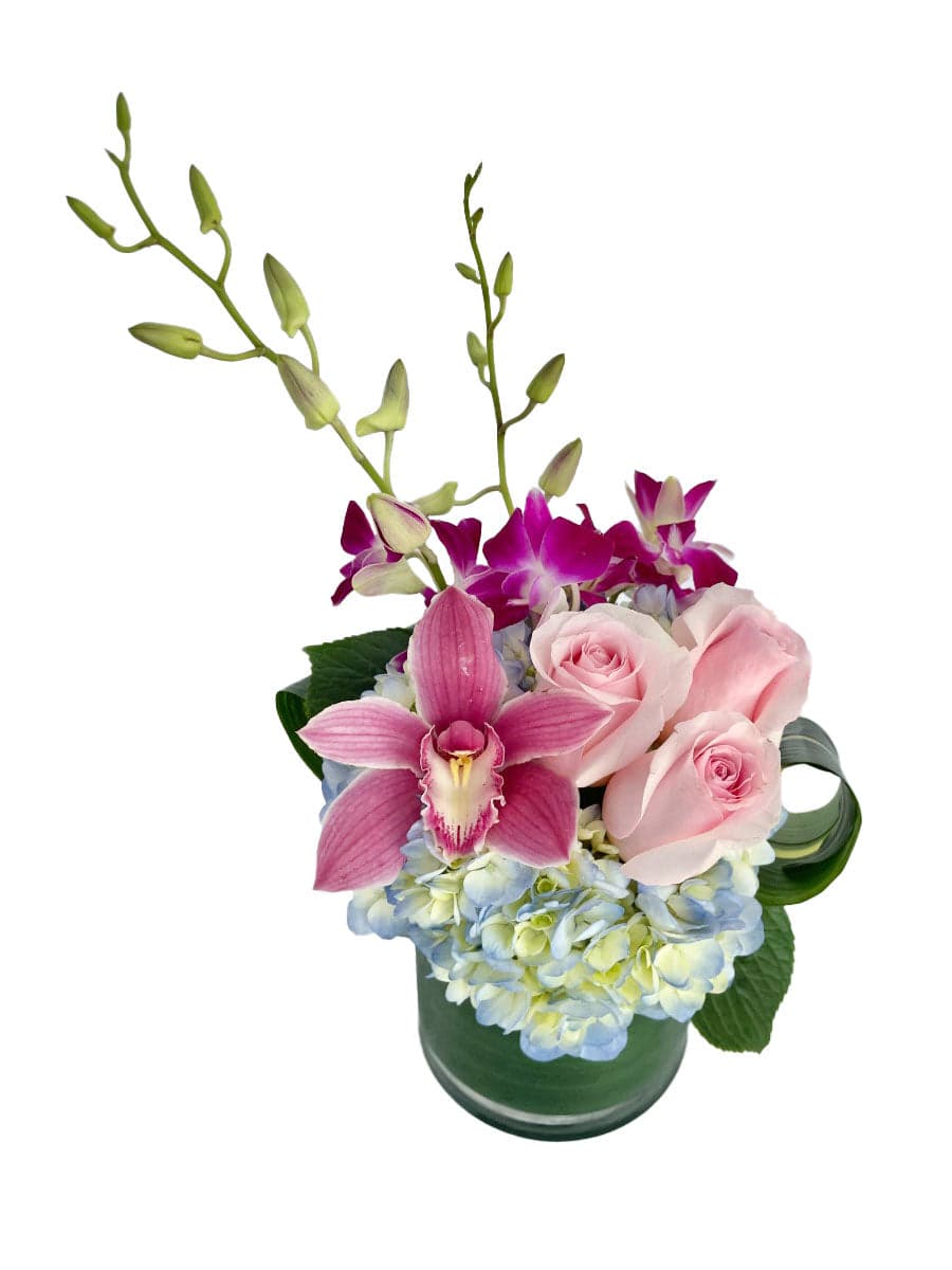 A vibrant arrangement of pink roses, orchids, and hydrangeas in a clear glass vase. Perfect for any special occasion.