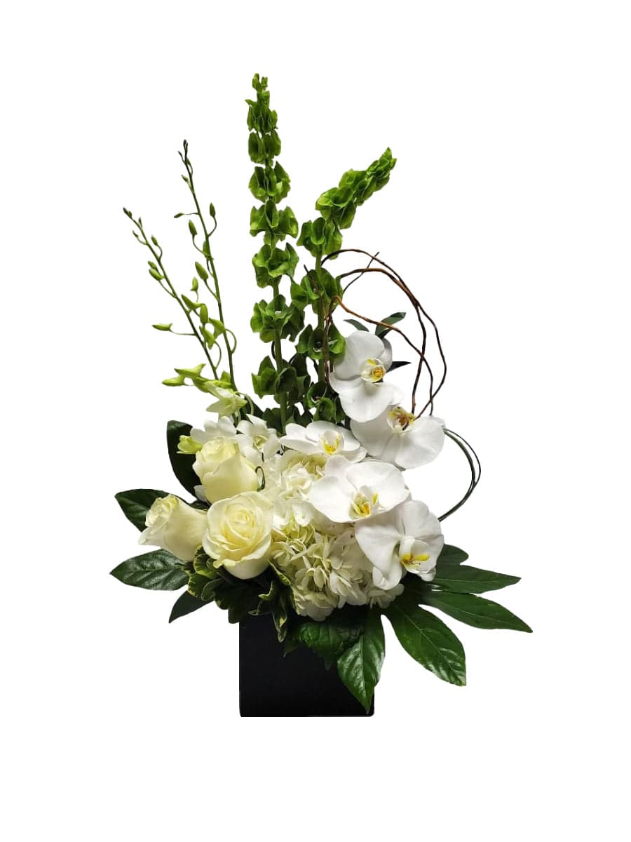 Elegant floral arrangement featuring white orchids, roses, and lush greenery in a sleek black vase.