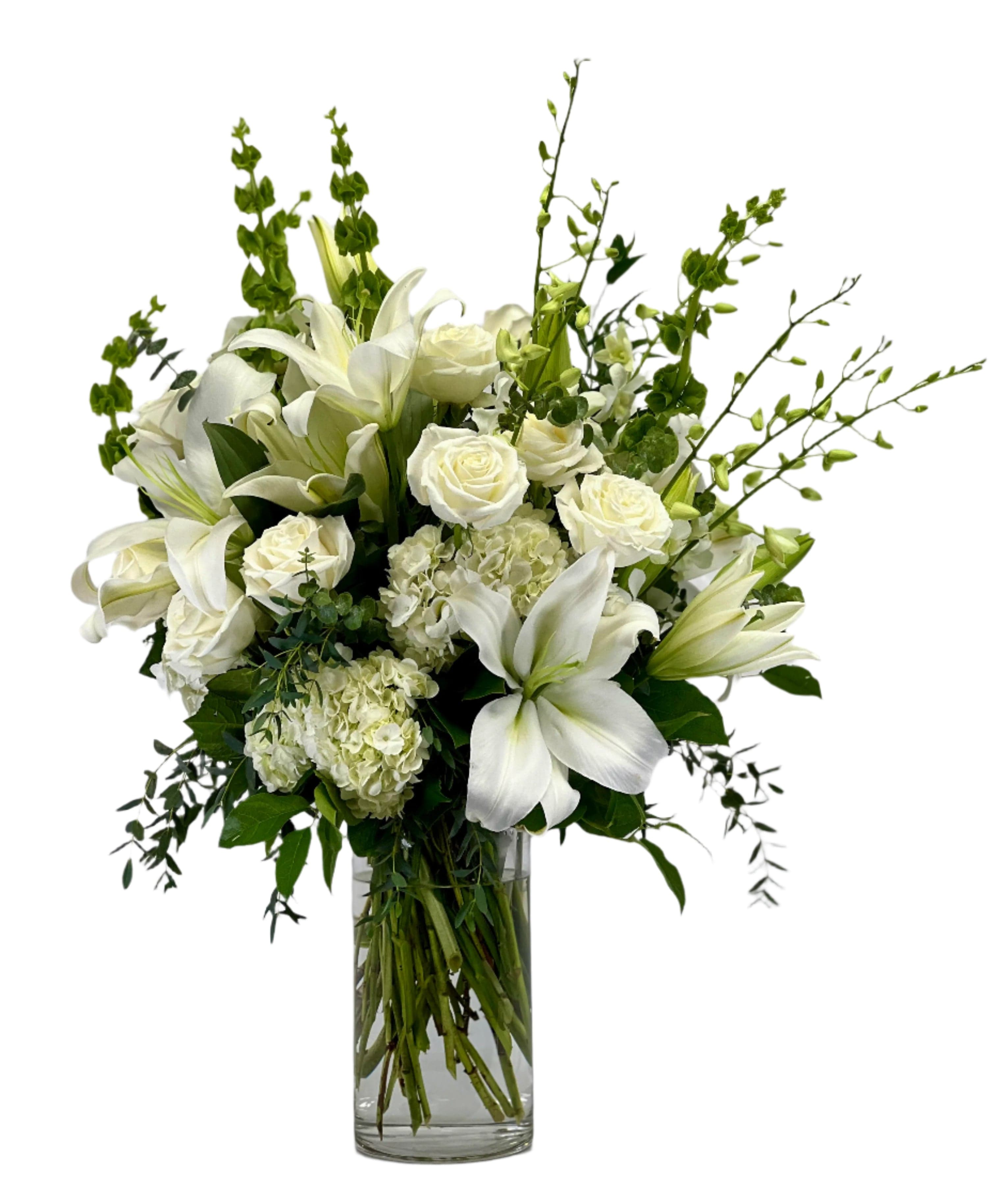 Elegant white floral arrangement featuring lilies, roses, and greenery in a modern glass vase. Perfect for any occasion.