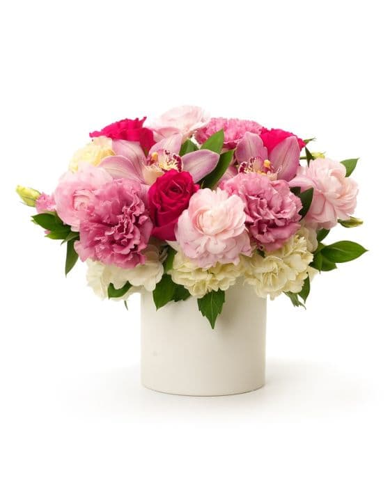 Vibrant floral arrangement featuring pink peonies, roses, and orchids in a stylish white vase.