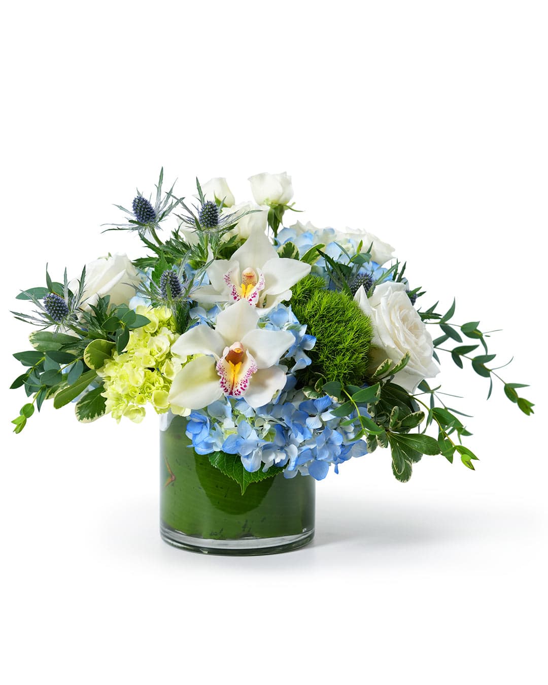 Vibrant floral arrangement featuring orchids, hydrangeas, roses, and greenery in a classic glass vase.