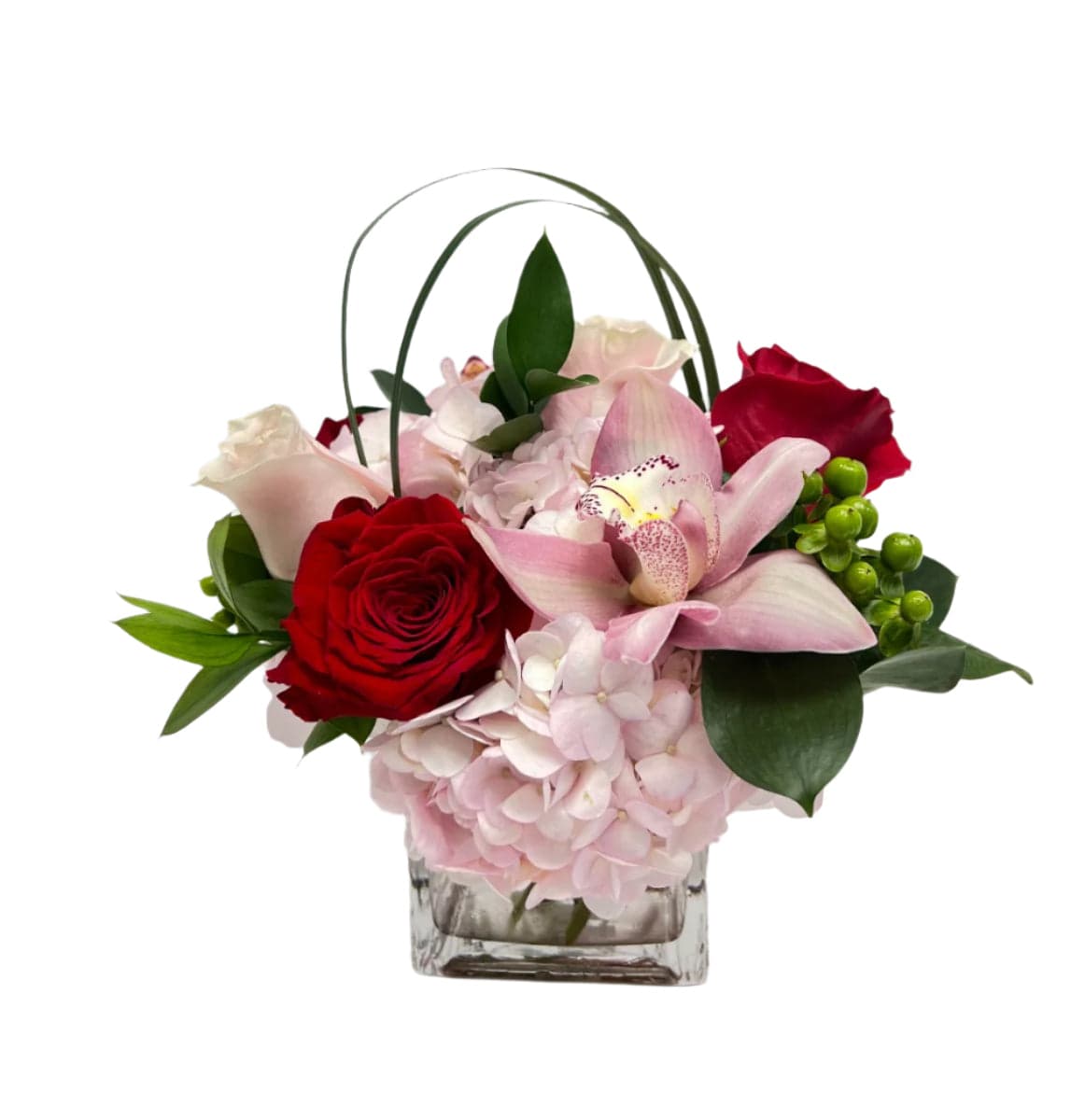 Elegant floral arrangement featuring pink orchids, red roses, and lush greenery in a stylish glass vase.