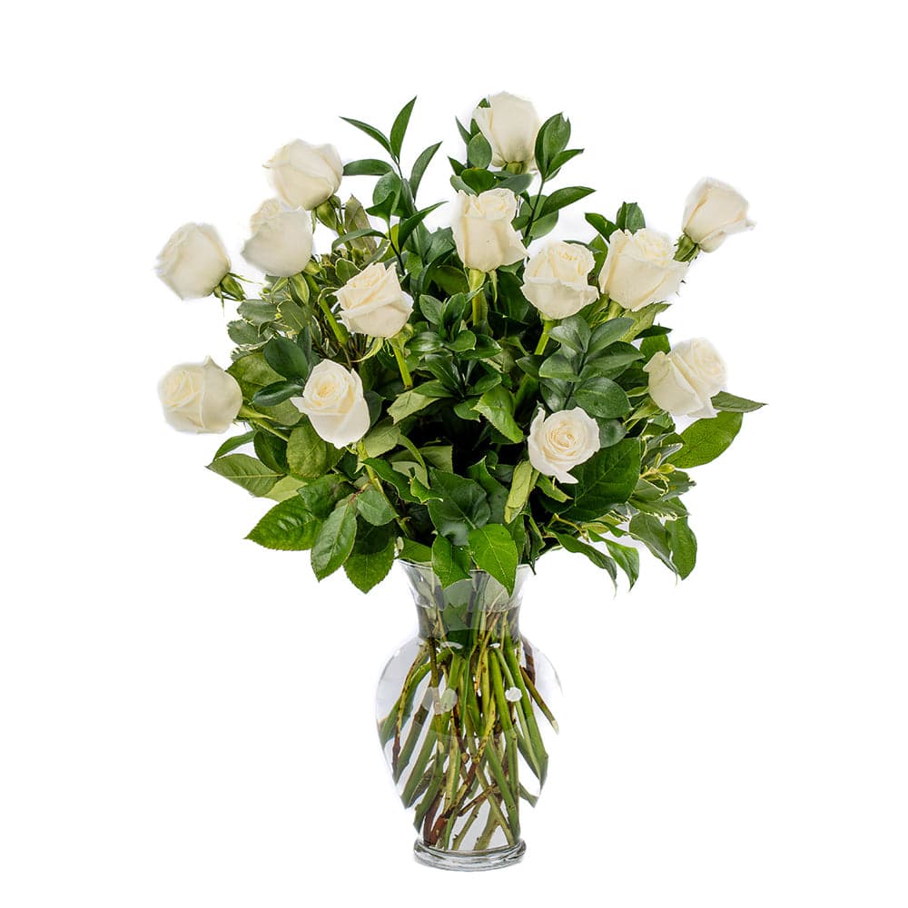 A stunning arrangement of white roses and lush greenery in a clear glass vase, perfect for any occasion.