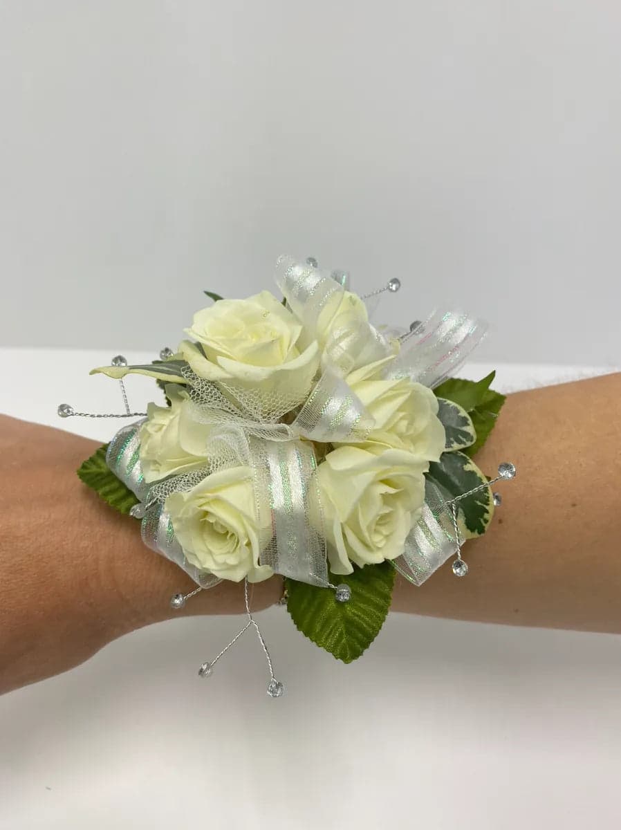 Elegant white rose wrist corsage adorned with sparkling ribbons and delicate beads for special occasions.